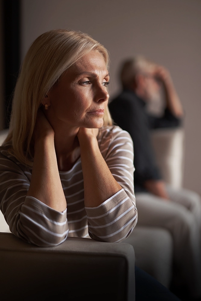 Woman sitting apart from her spouse as growing distance and repeated conflict lead her to consider whether speaking with a divorce lawyer in Rego Park could help clarify what comes next