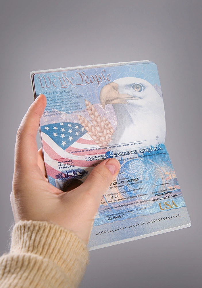 Hand holding an open U.S. passport and visa, reflecting the immigration independence someone may be trying to protect with help from a VAWA Immigration Lawyer in Rego Park