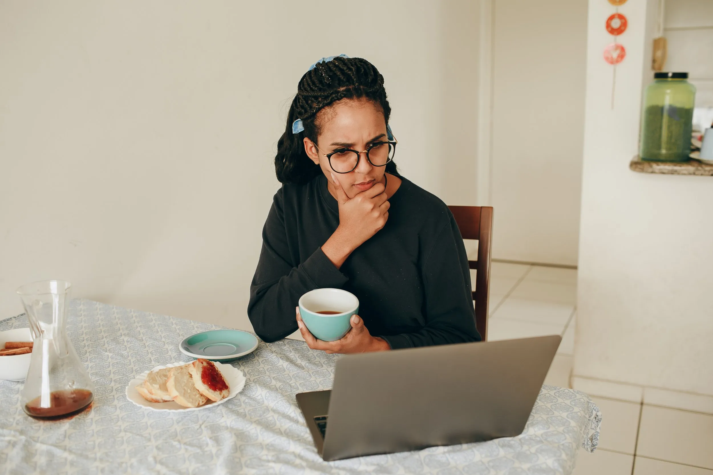 A woman looking at her laptop in deep thought