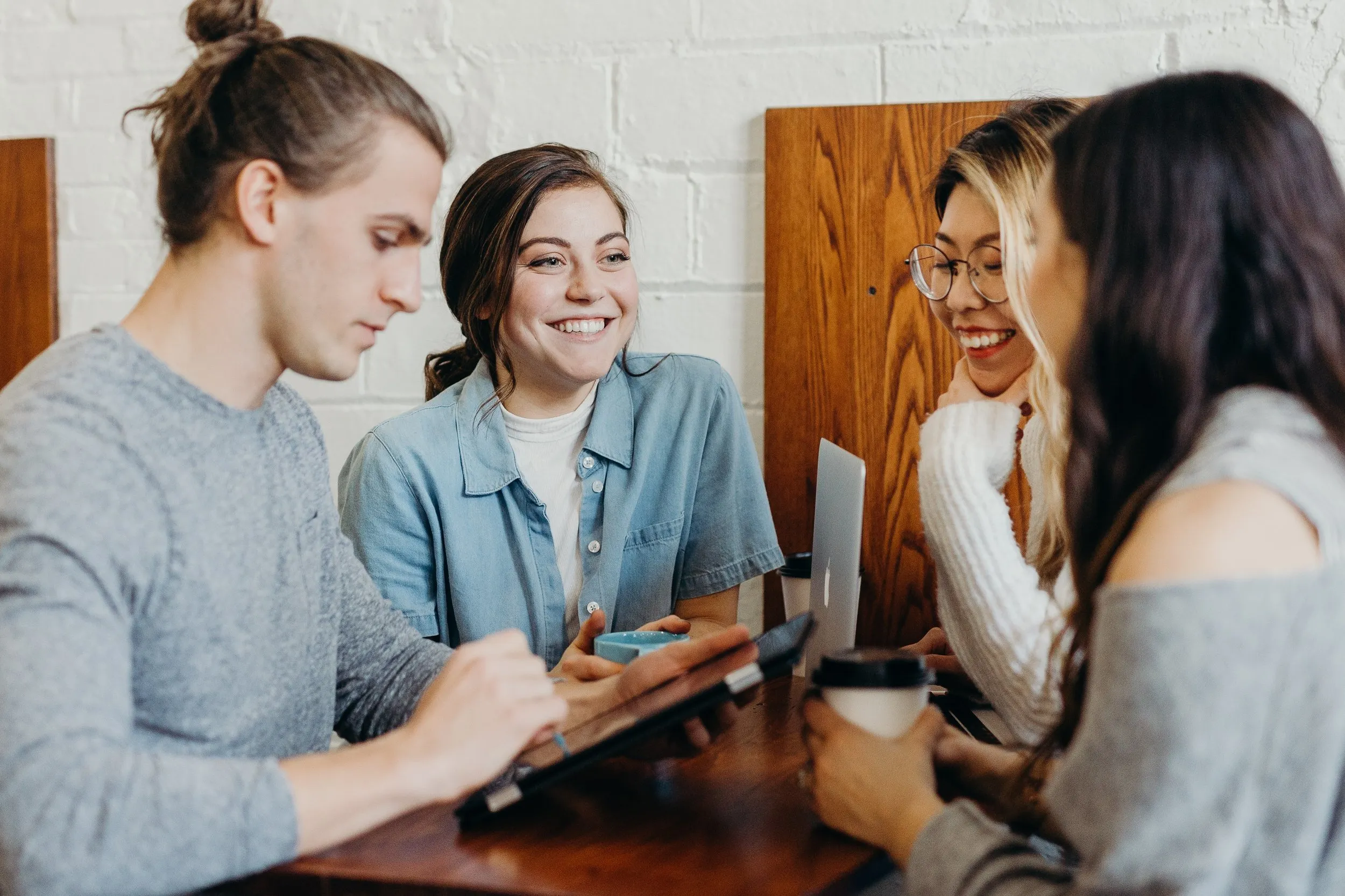 Group of men and women smiling around their computers and tablets