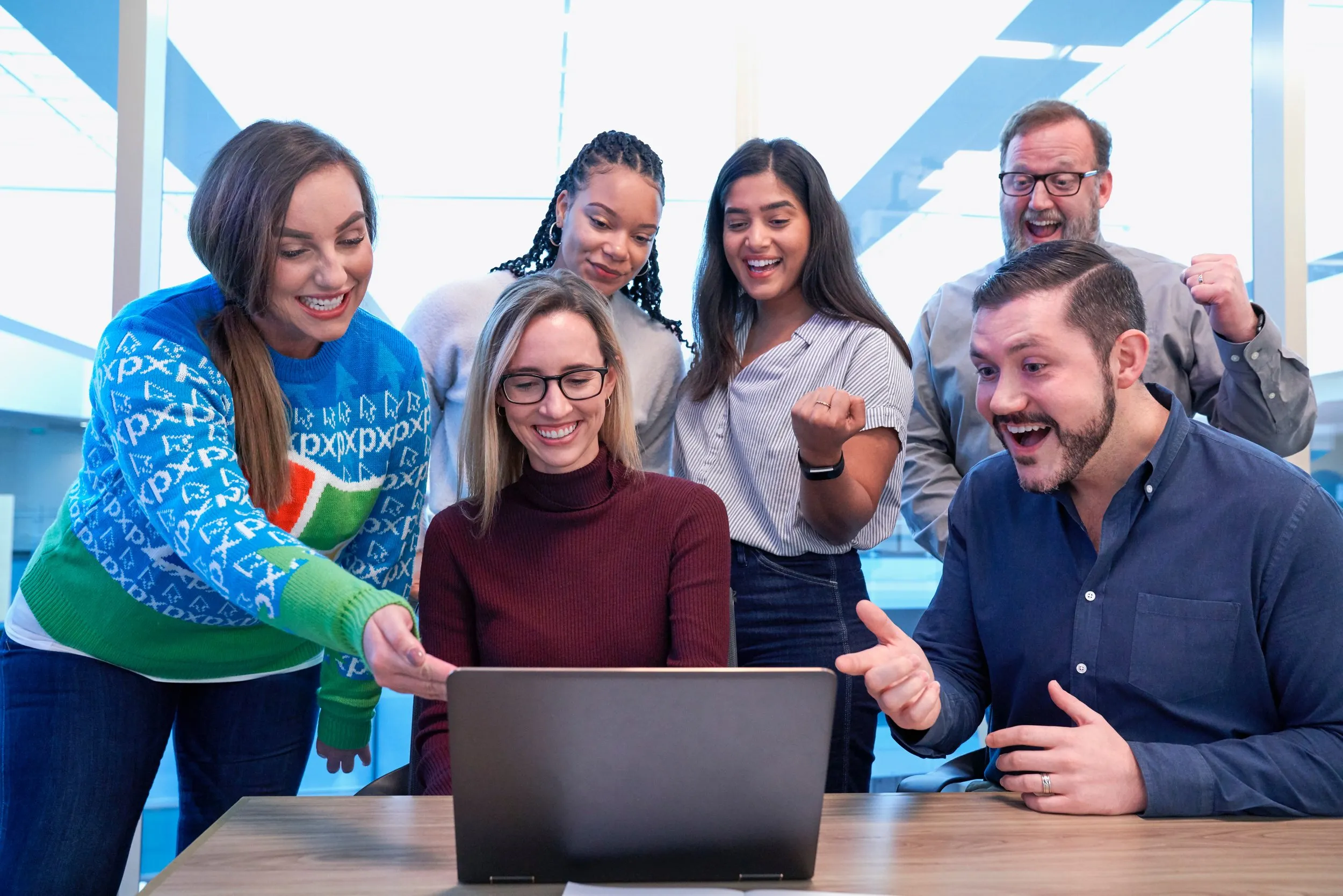 People sitting around a computer screen looking excited