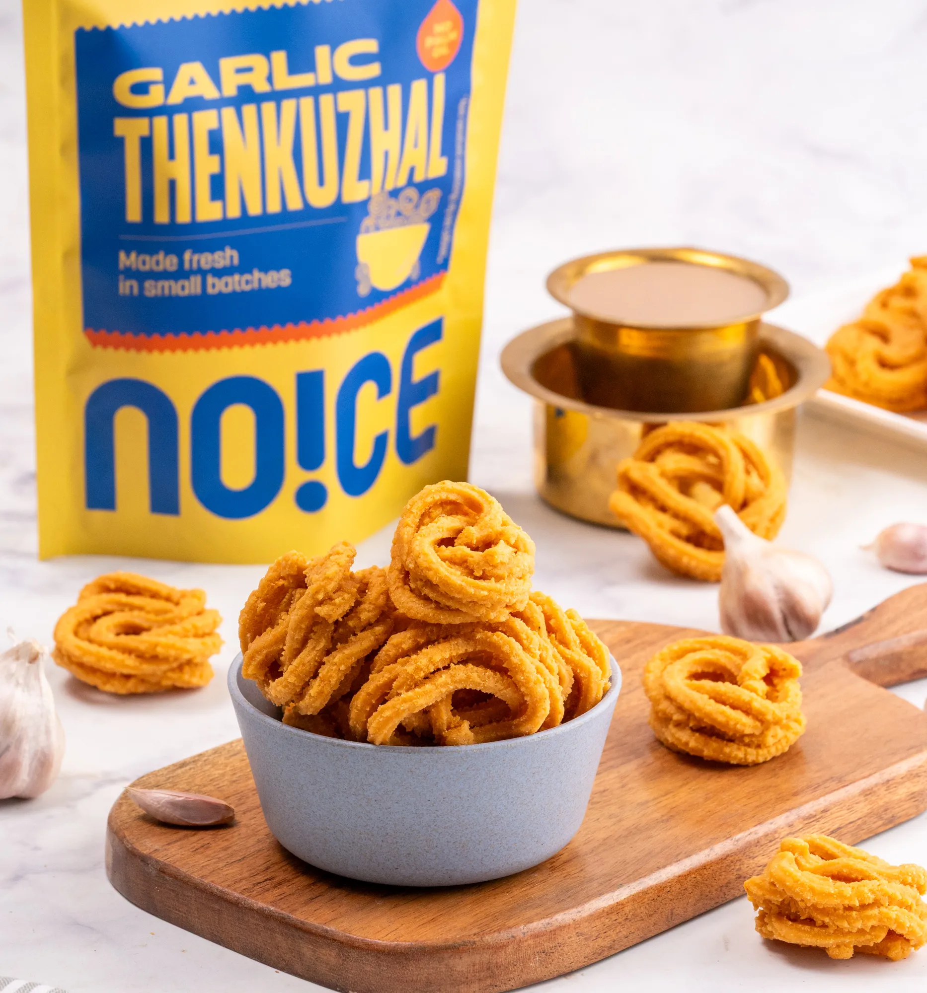 NOICE Garlic Thenkuzhal, crispy and golden savory rice flour spirals with a rich garlic flavor, handcrafted without palm oil or artificial additives