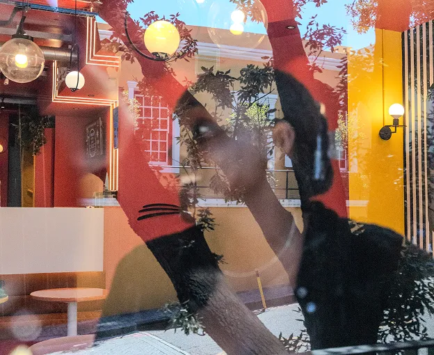 Reflection of a woman behind glass with a large red circle and outdoor trees visible