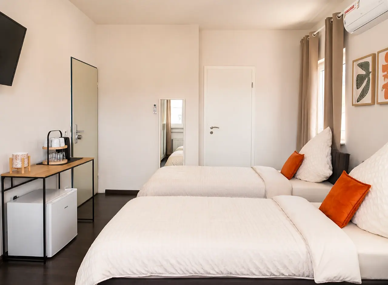 Zimmer bei BASE stay Erlangen mit Tea & Coffee-BASE und orangefarbenen Kissen