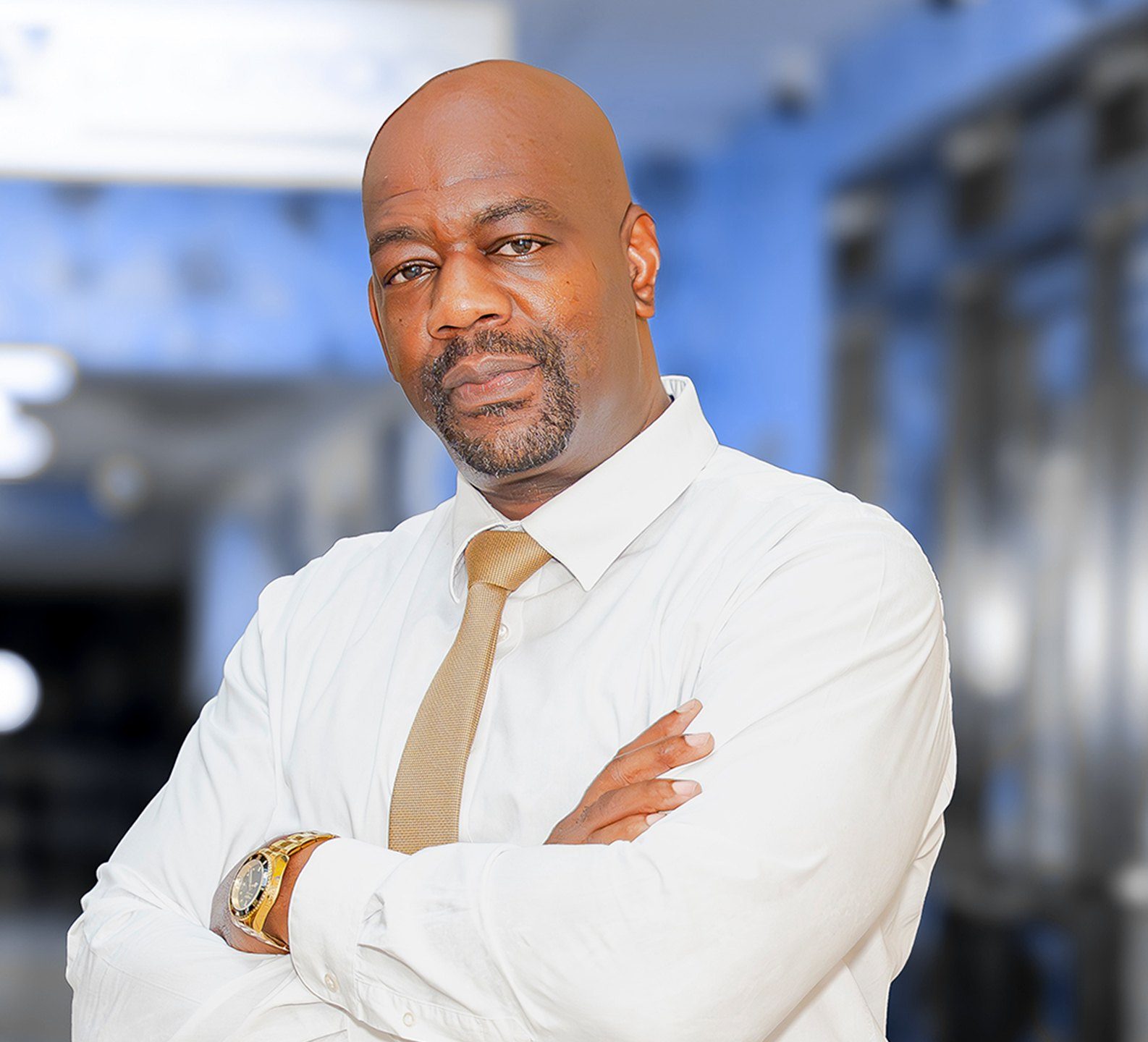 Dr. André Vaccianna in a white shirt and gold tie, arms crossed