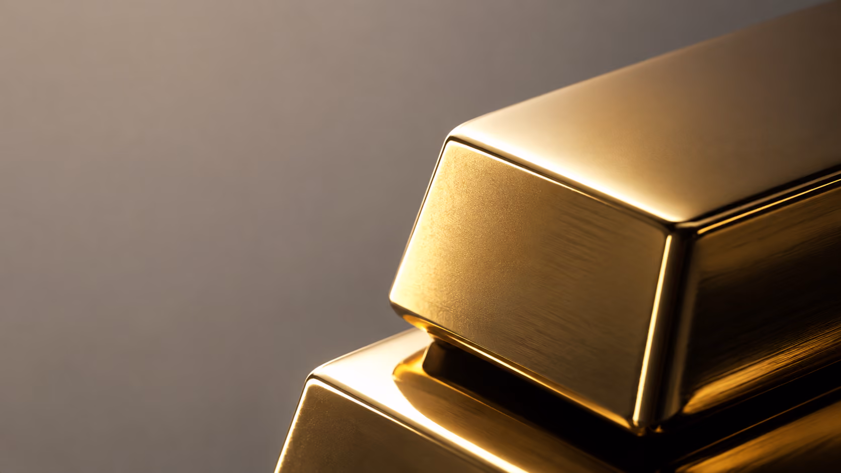 Close-up of two shiny gold bars stacked with a smooth reflective surface and soft gradient background.