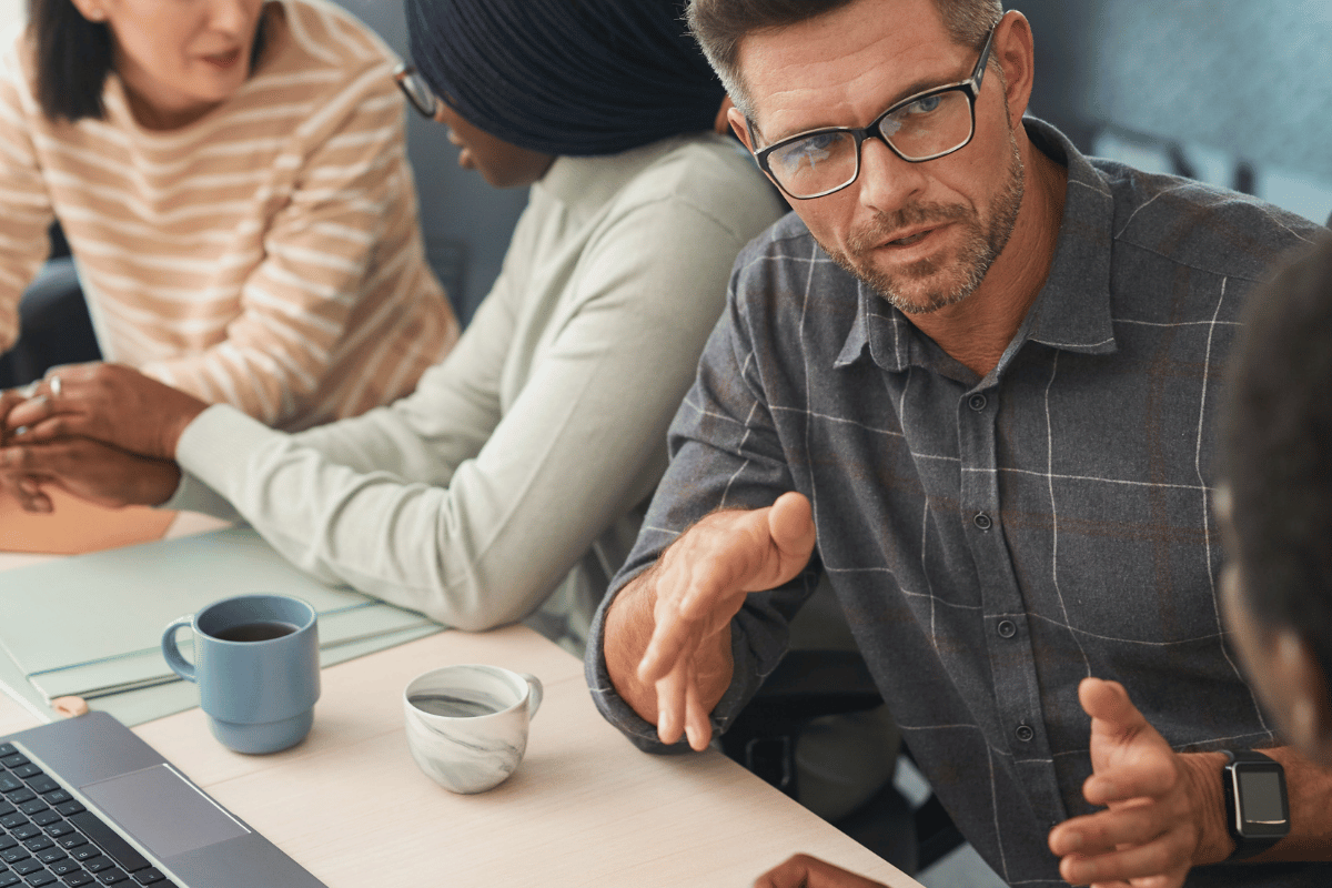 Focused man in glasses leading a team discussion at a work table.