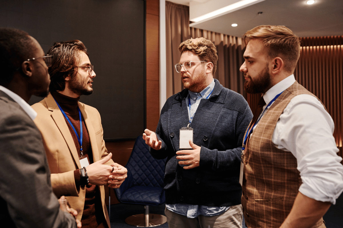Four male professionals in a serious meeting with lanyards.