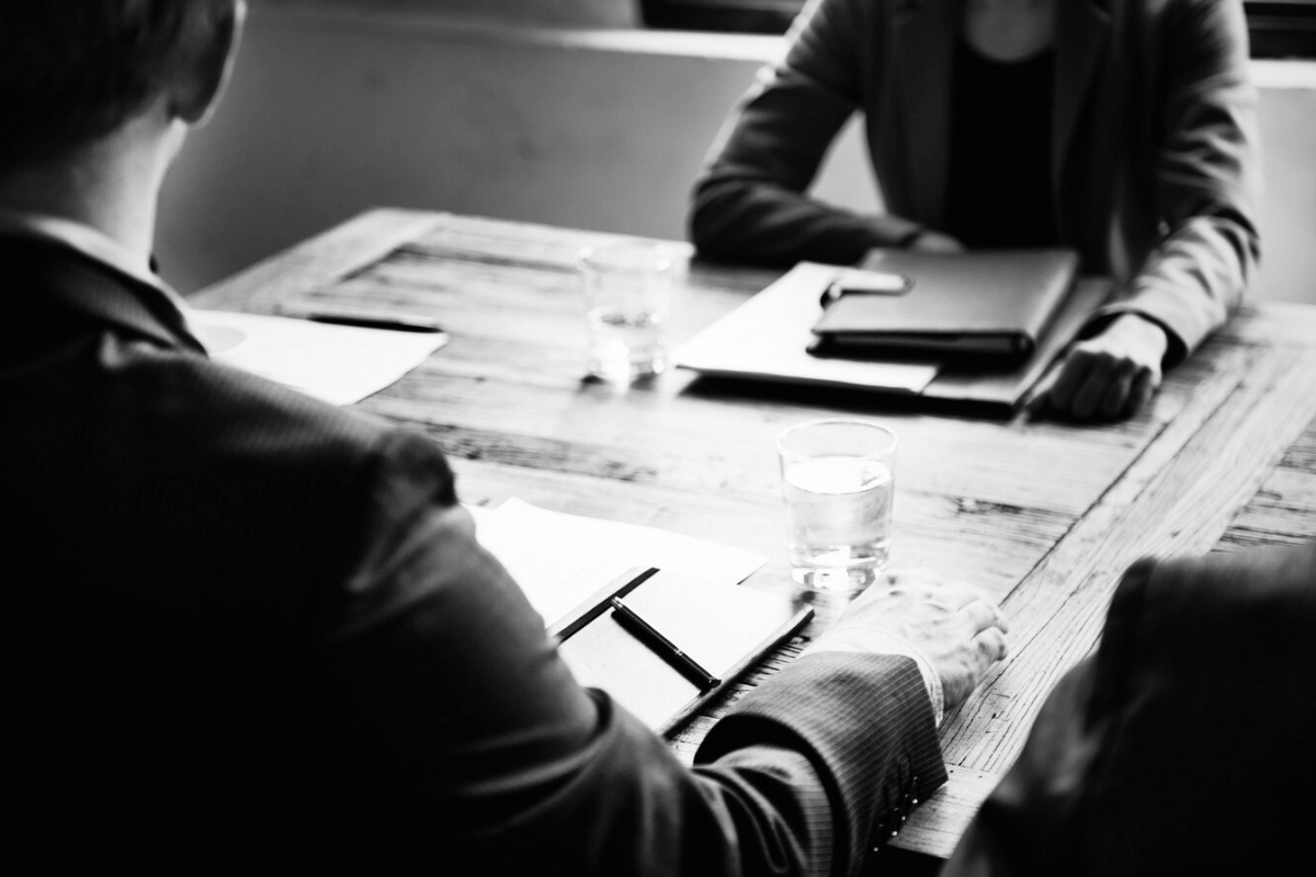 A black and white photo of two business people sitting at a table.