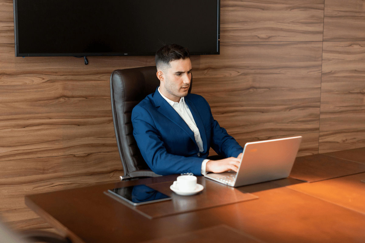 Professional businessman concentrating on his laptop in a stylish office with wooden paneling.