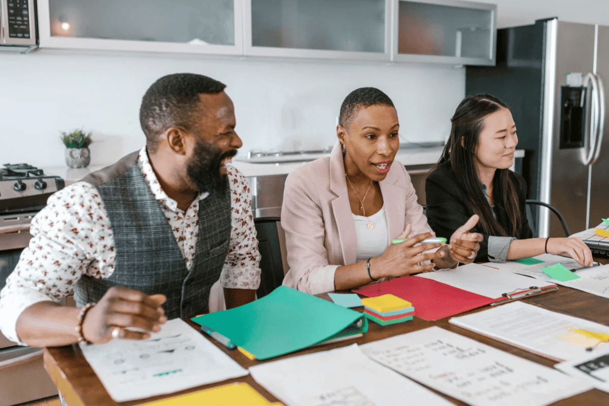 Diverse group of professionals actively discussing documents at a kitchen table.