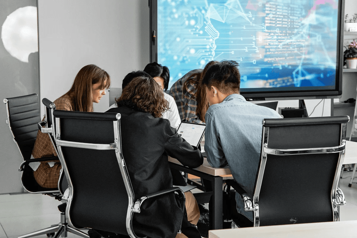Team of professionals analyzing digital data on screen.