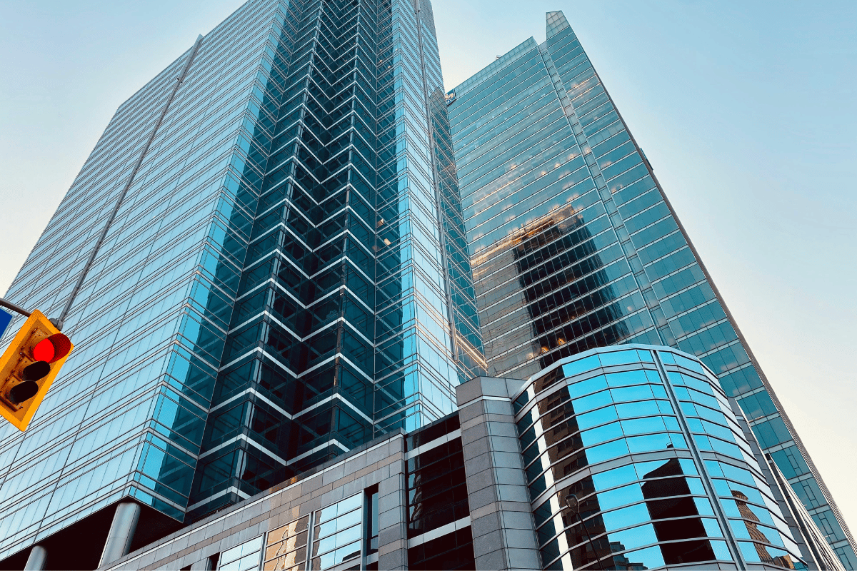 Modern skyscrapers with reflective glass facades towering under a clear blue sky, intersected by traffic lights.
