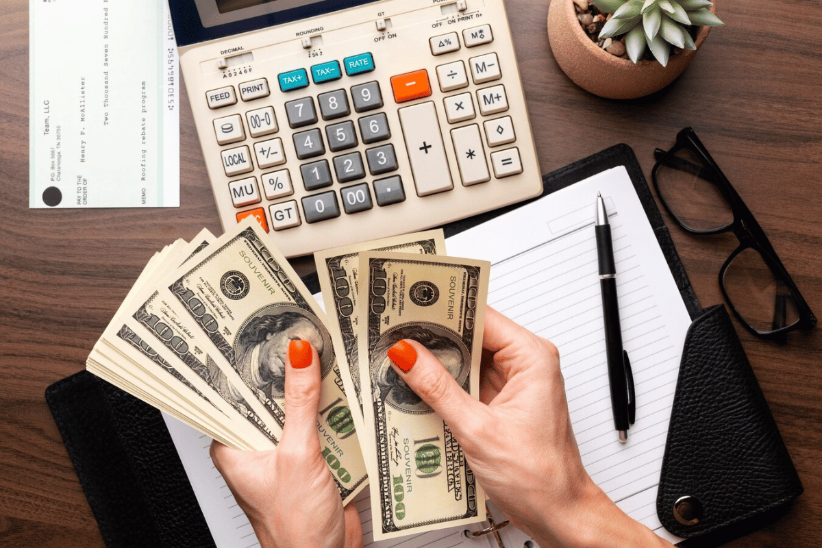 Business financial planning with cash, calculator, and notepad on wooden table.