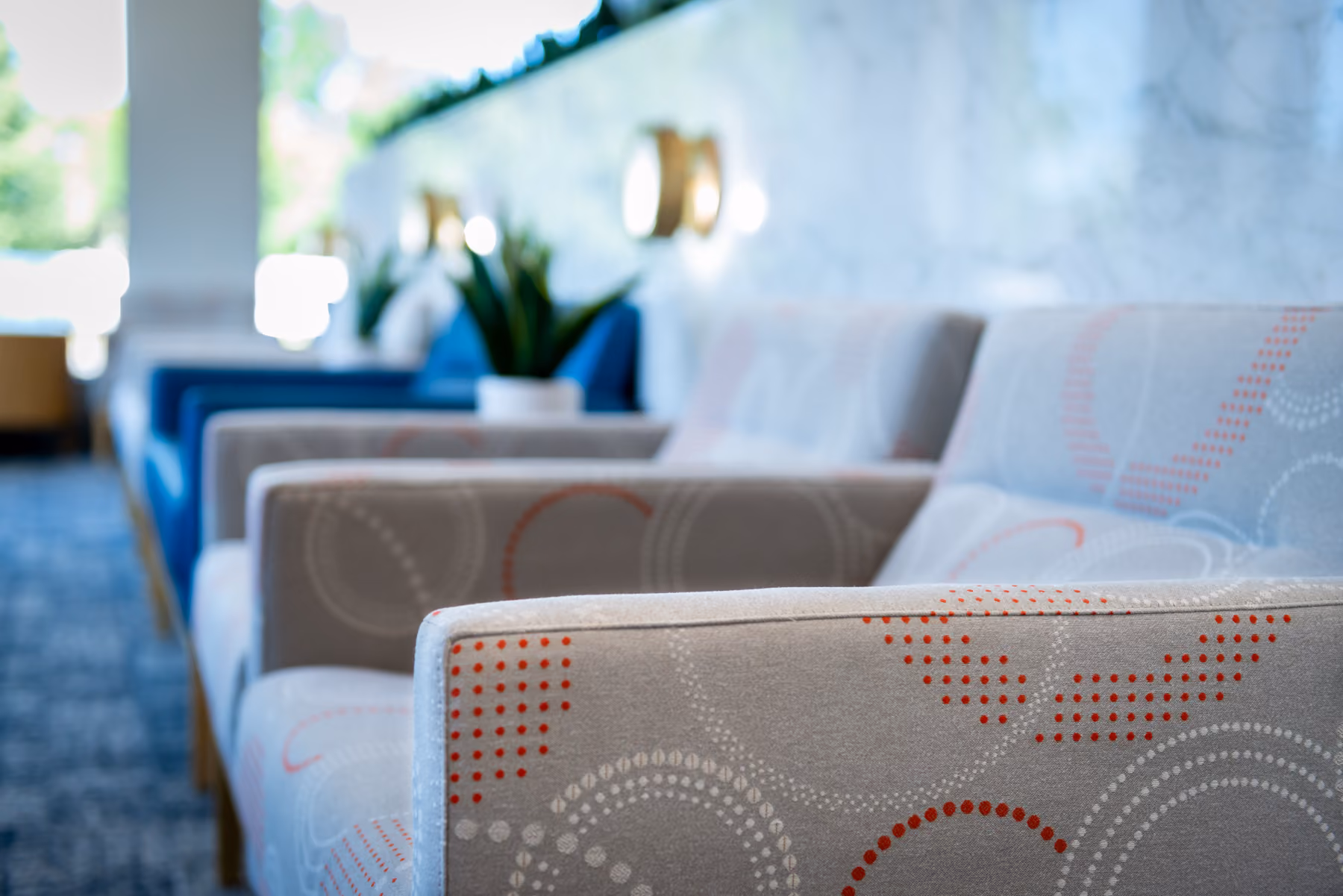 Row of modern armchairs with patterned fabric in a bright lounge area.