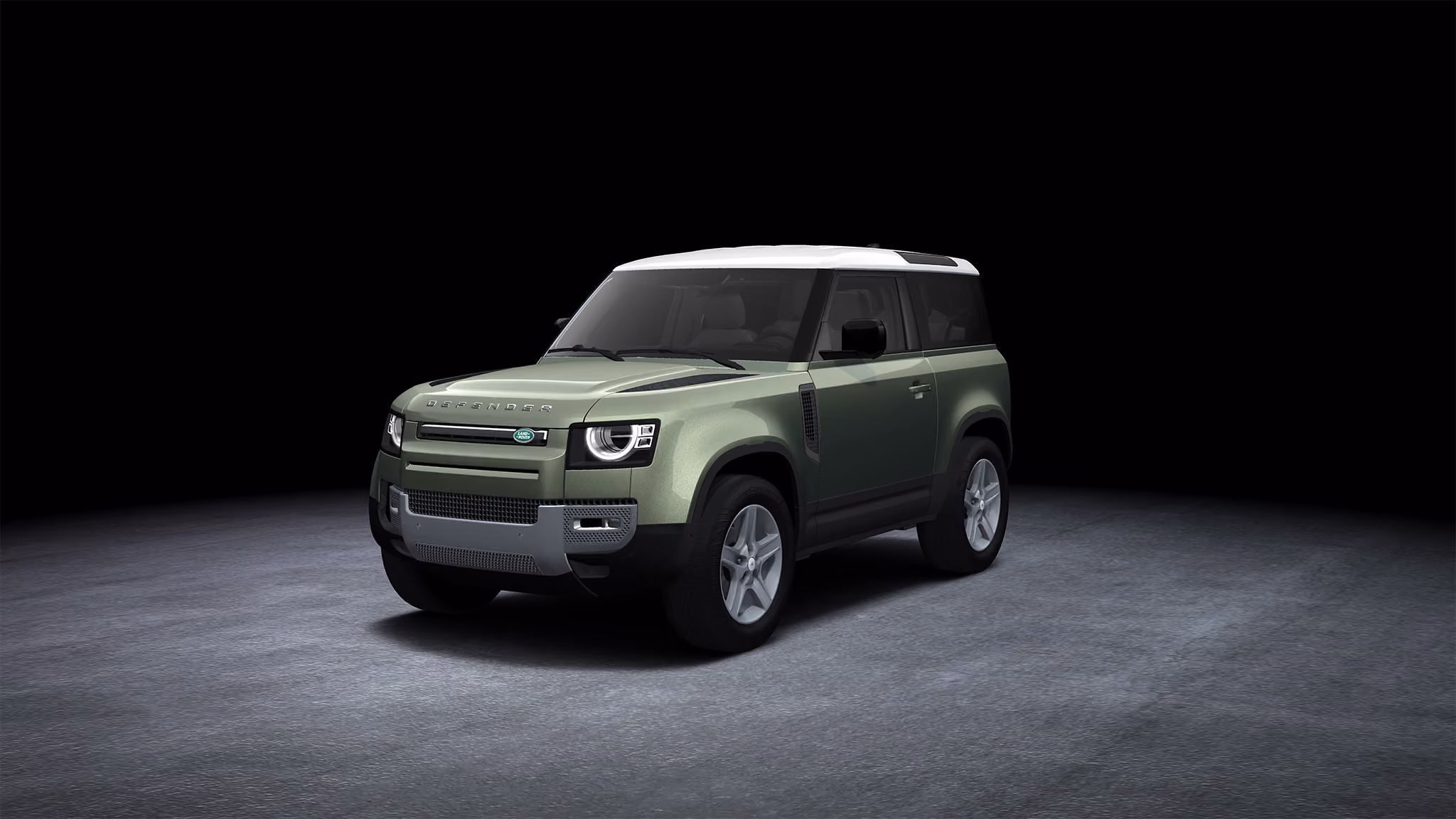 Green Land Rover Defender with white roof on dark gray surface and black background.