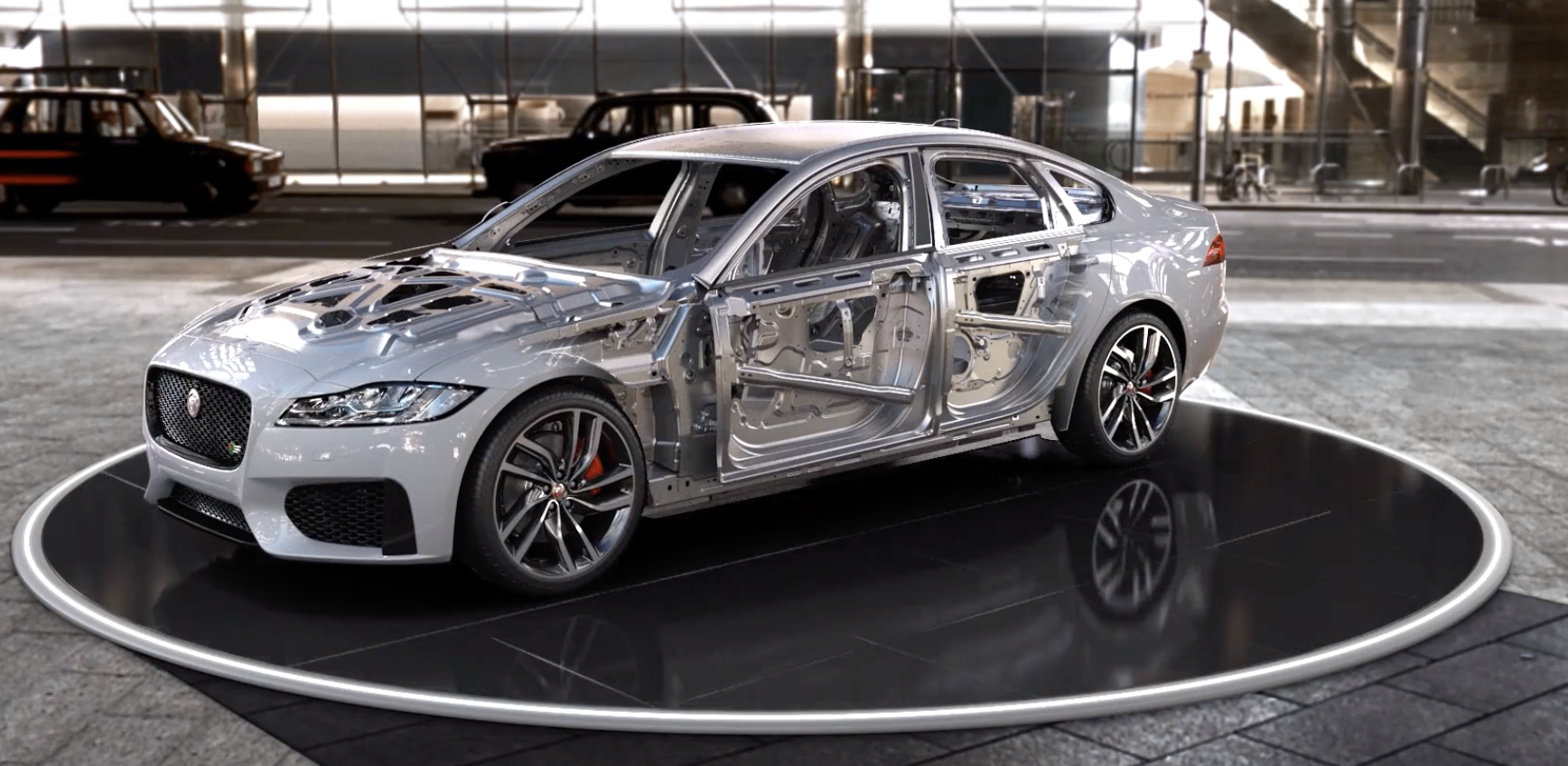 Jaguar car with half of its bodywork removed to show internal structure on a circular platform.