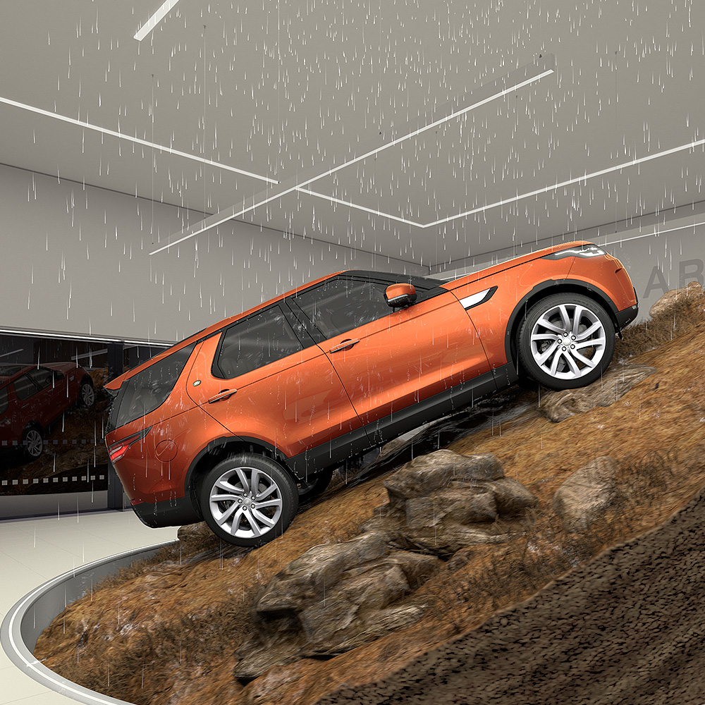 Orange SUV climbing rocky slope indoors with rain falling around it.