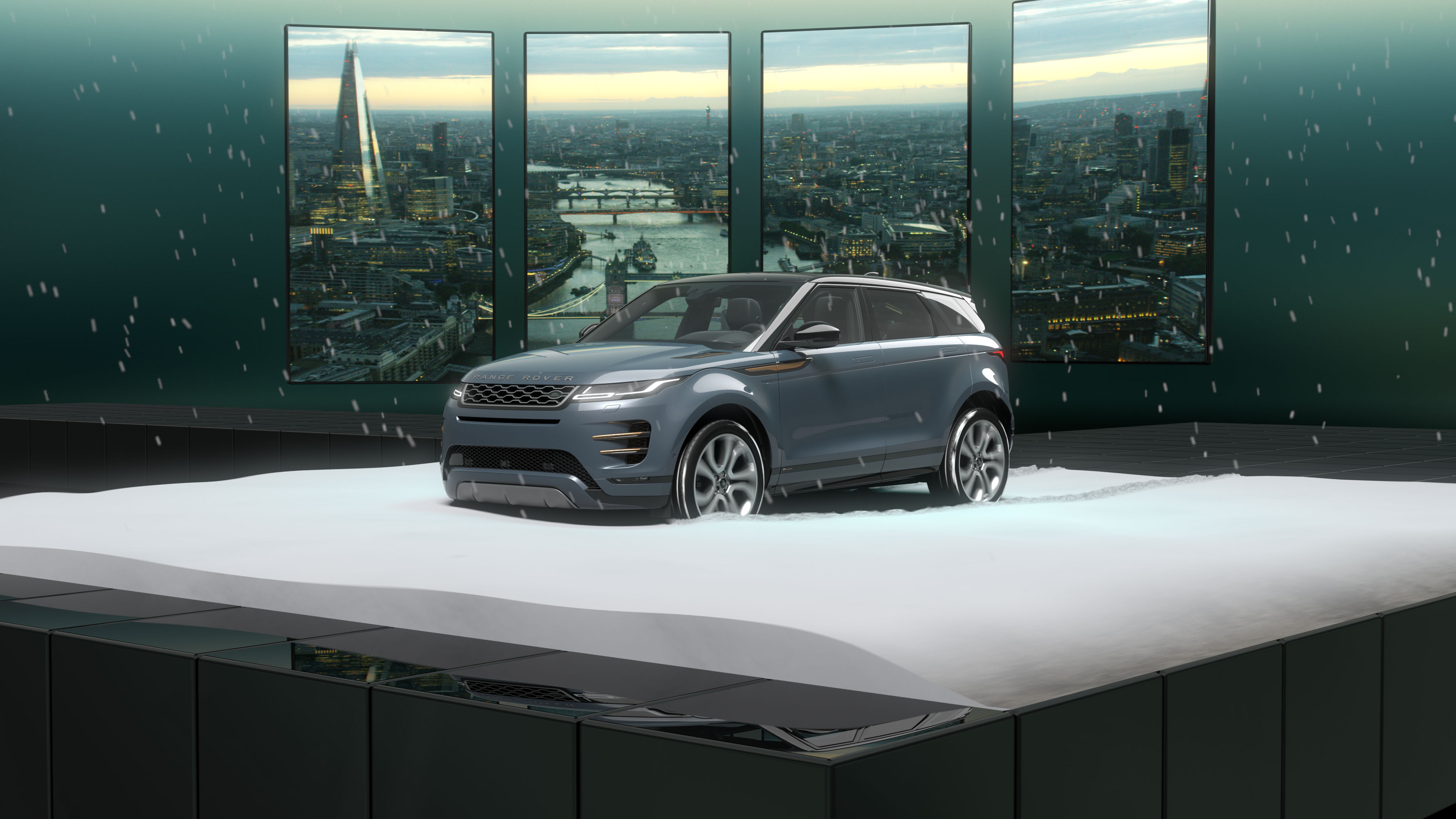 Blue Range Rover SUV displayed on snow with cityscape panels in the background and falling snowflakes.