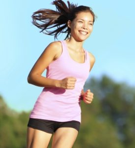 A smiling woman running outdoors