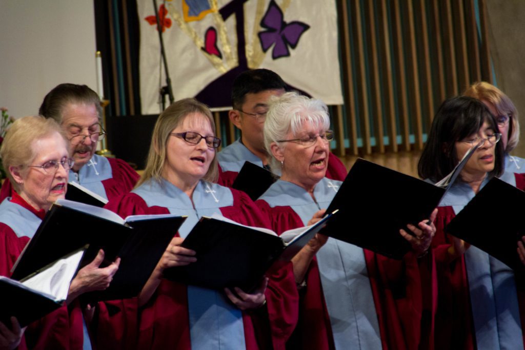 Choir members in red robes singing from songbooks