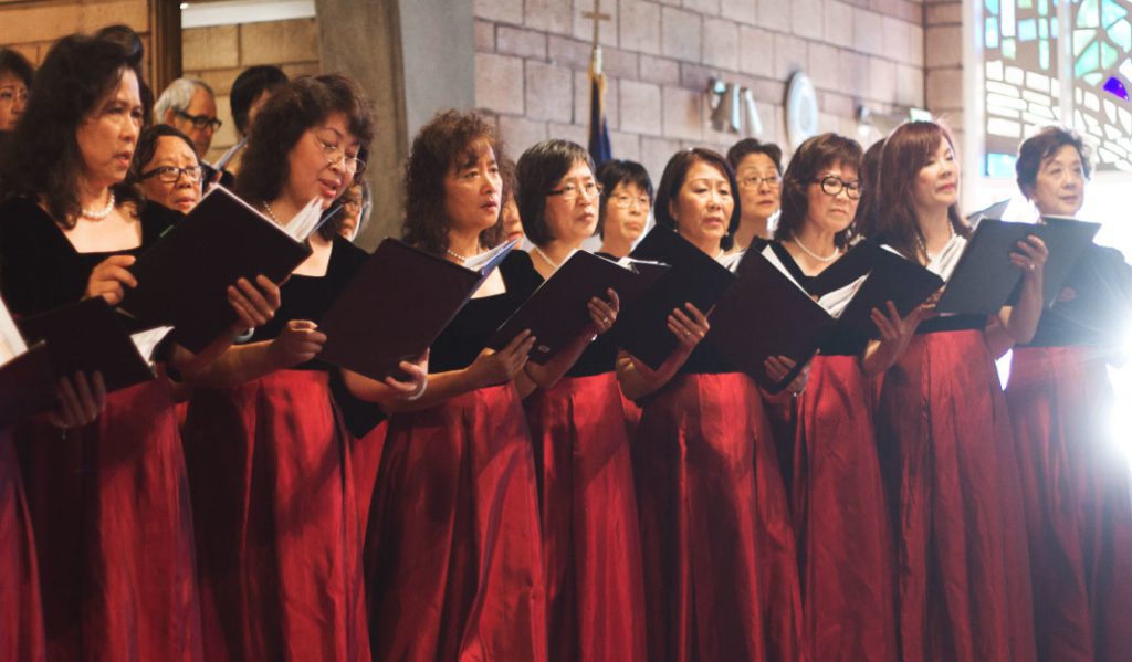 A women's choir in red and black performing in a church