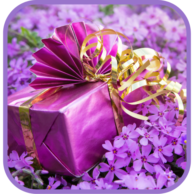A purple wrapped gift with gold ribbon among purple flowers