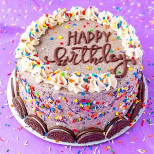 A birthday cake decorated with sprinkles and cookies