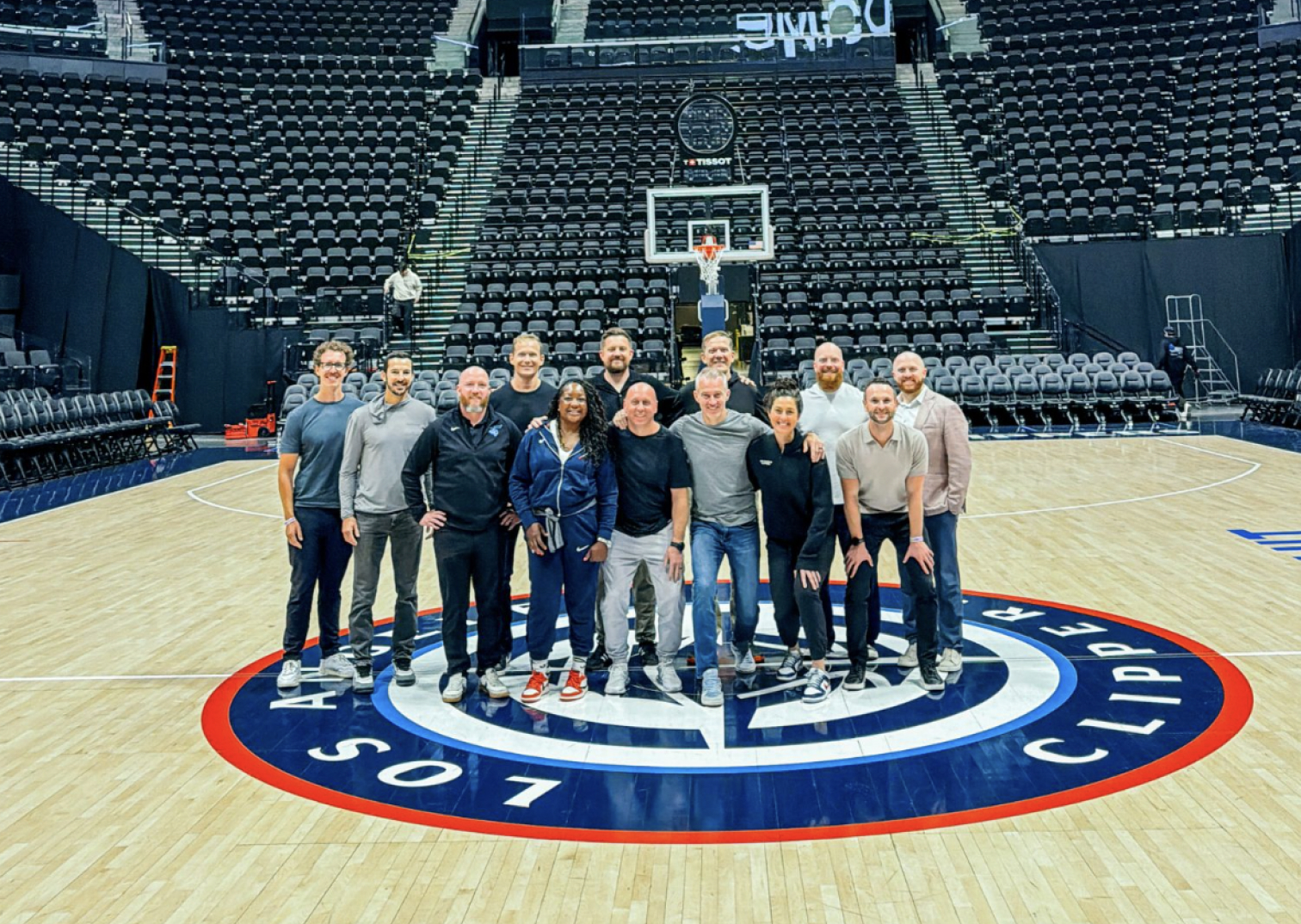 A group of performance staff standing on the centre court of an indoor basketball arena