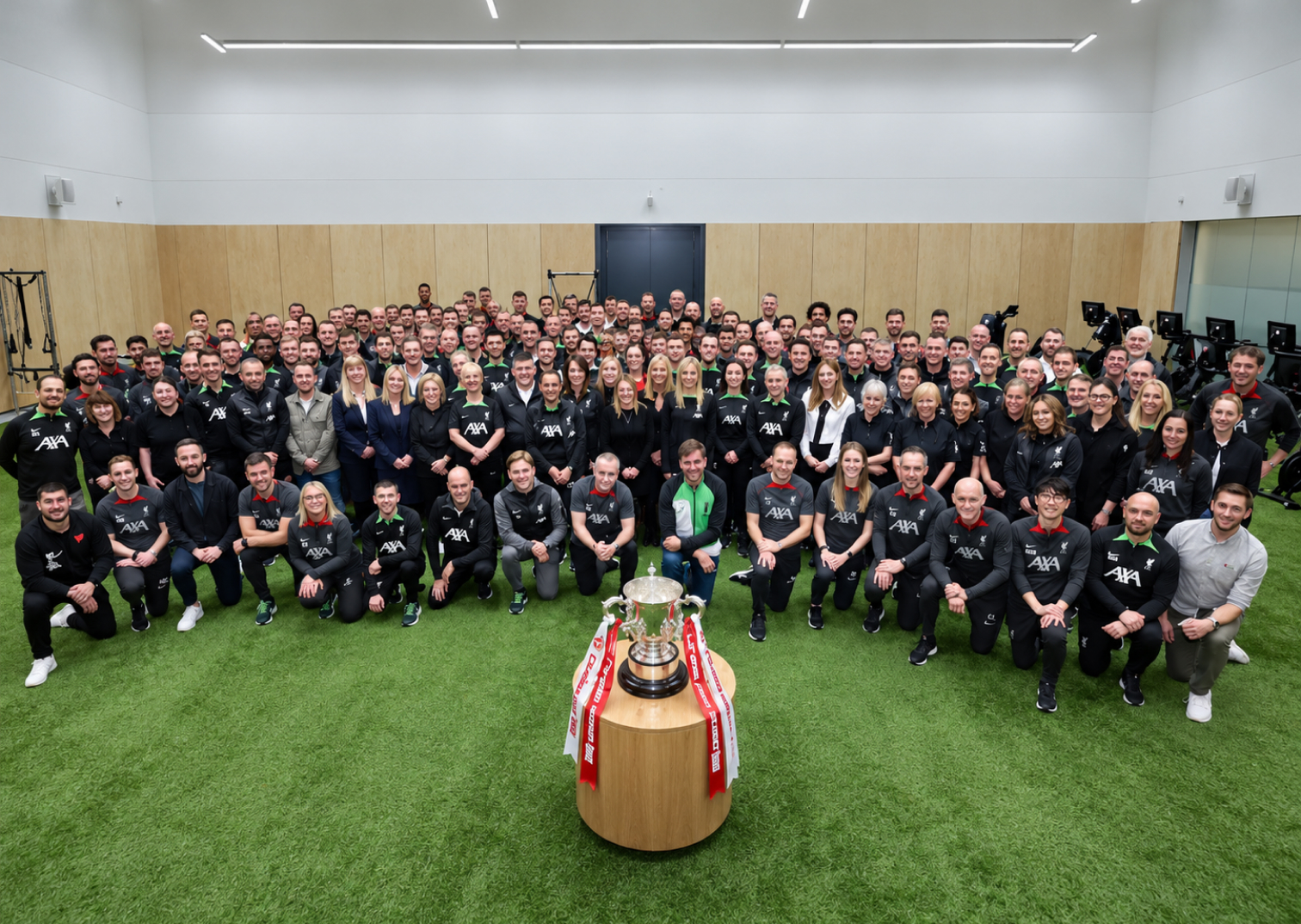 Liverpool FC academy and first-team staff gathered around the EFL Cup trophy