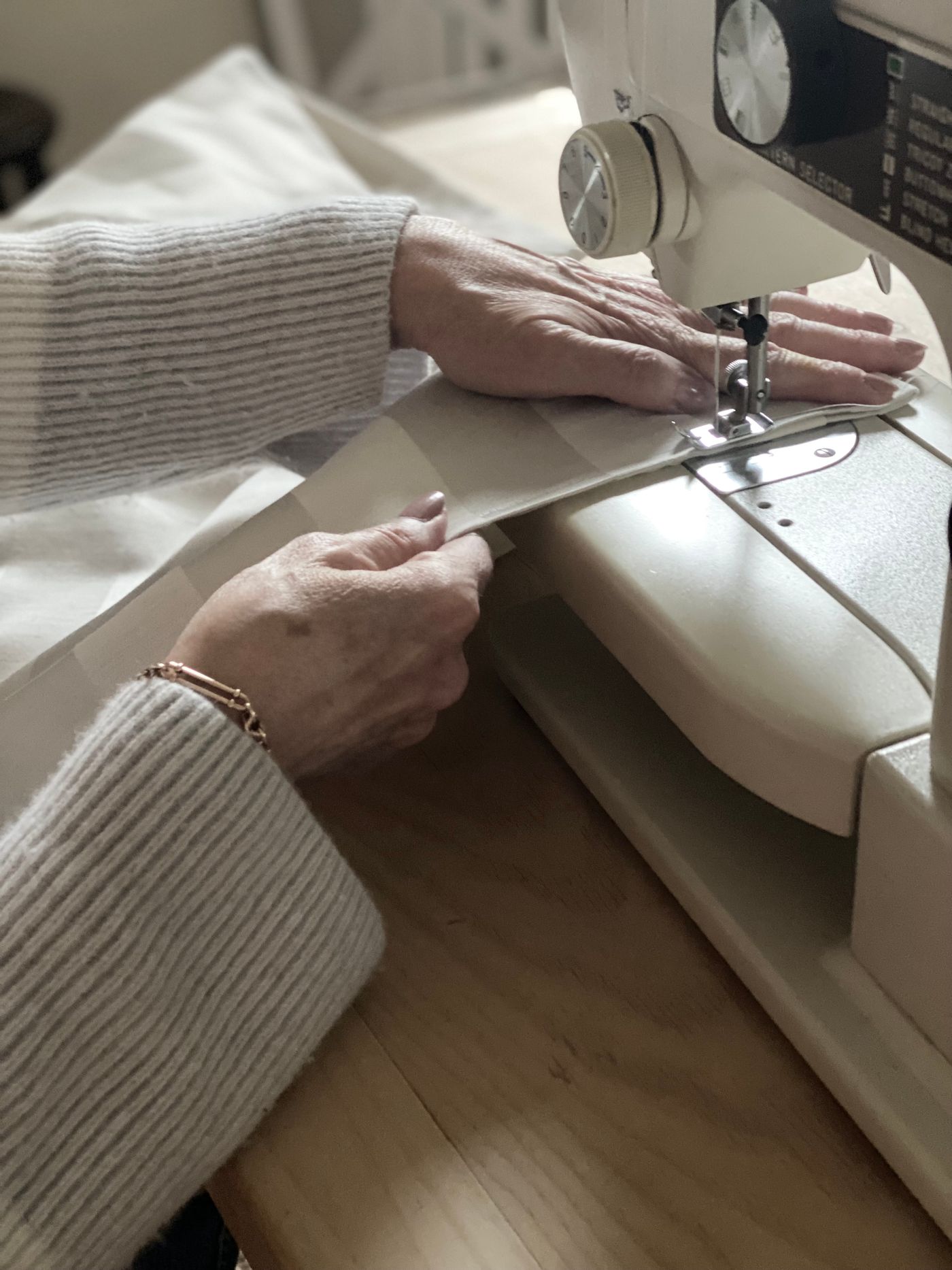 Hands guiding fabric through a sewing machine in a workshop