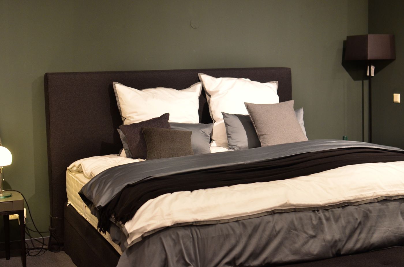 Dark-toned bedroom interior with neatly arranged bedding