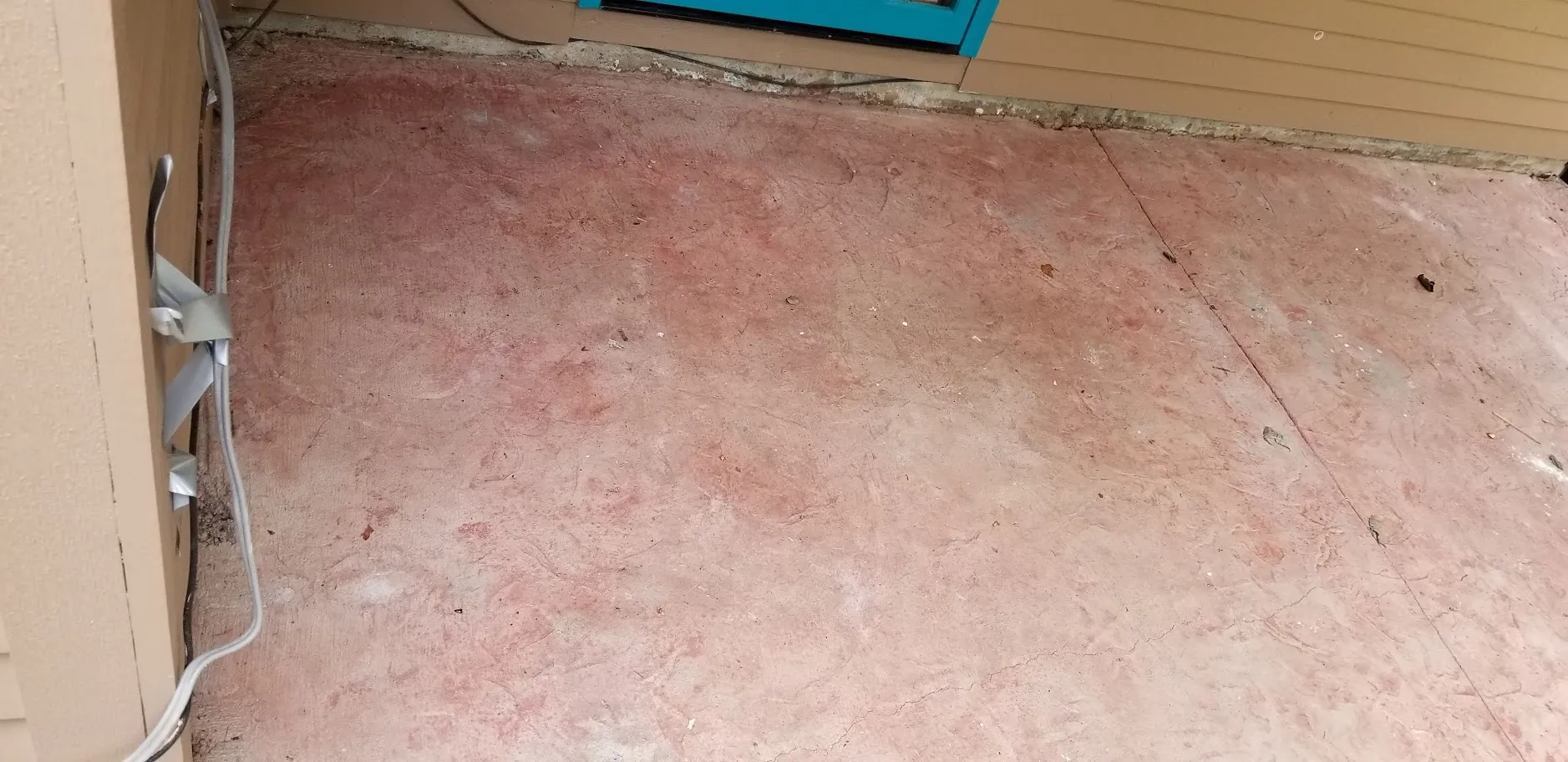 A colored concrete entry landing before restoration, the red finish faded, chalky and soiled