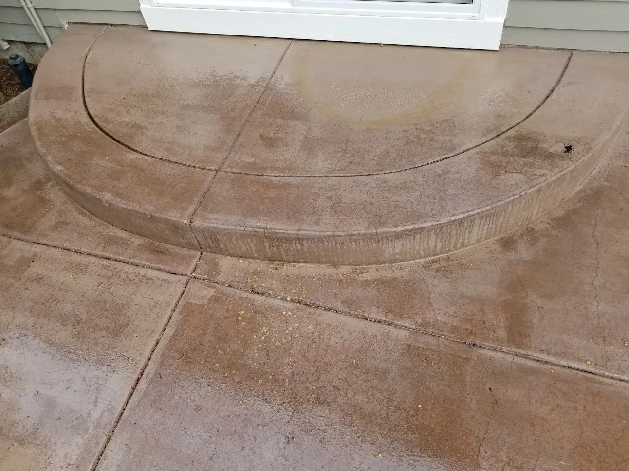 Curved concrete entry step and patio before restoration, with dark water streaking down the step face