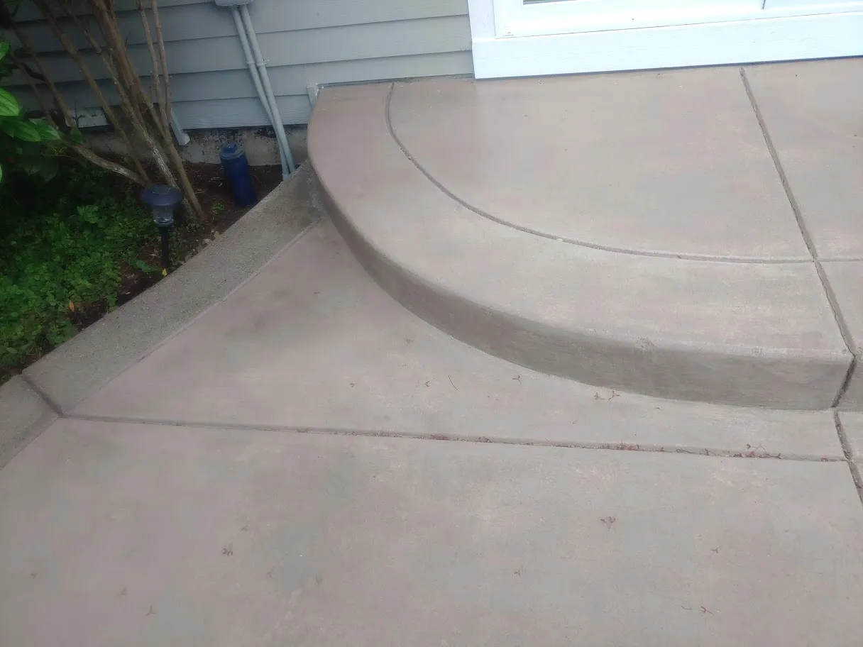 The same curved concrete step and patio after restoration, with the streaking removed and an even tone across the slab