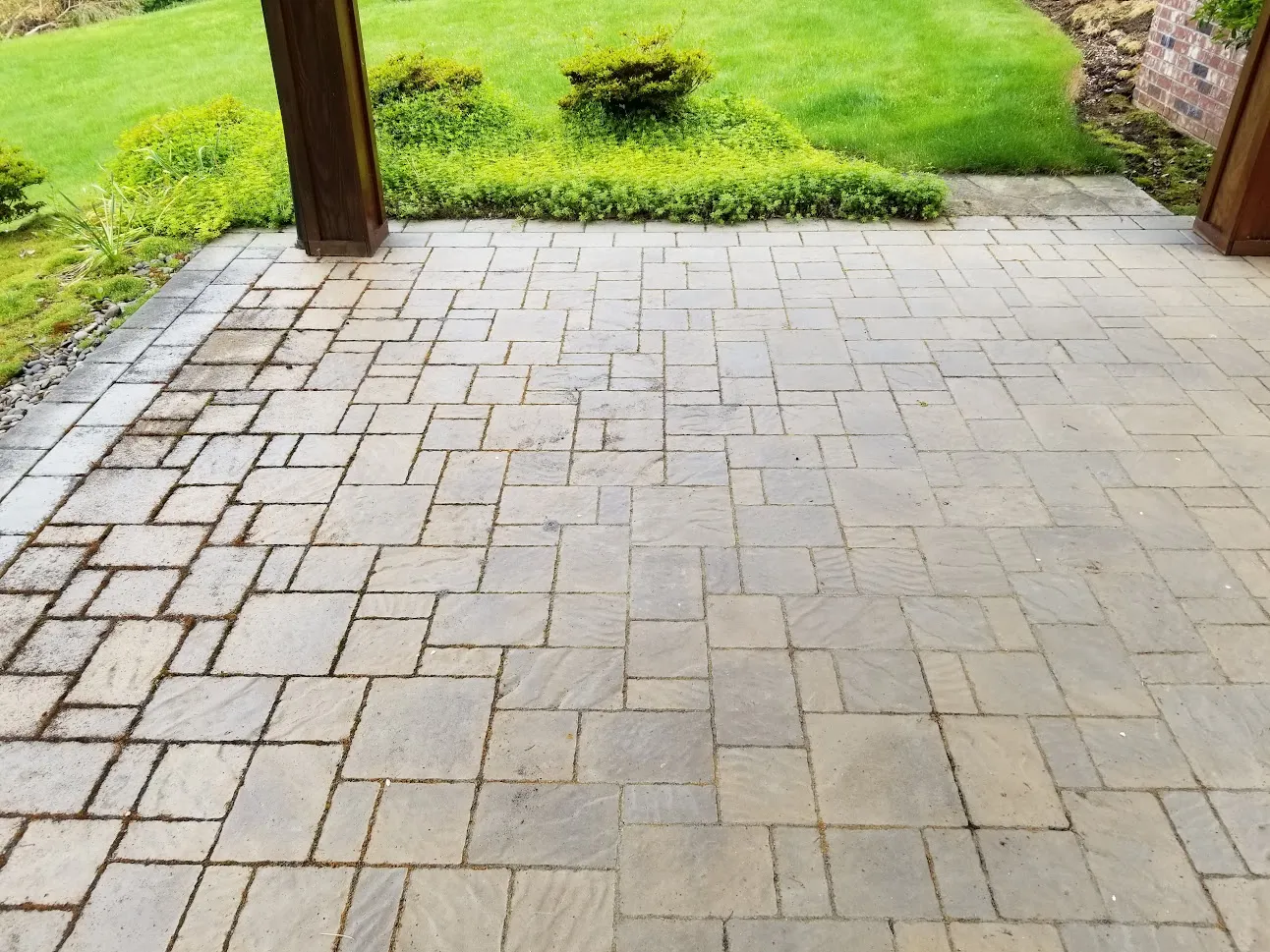 Large paver patio before restoration, with weeds and moss in the joints and washed-out joint sand