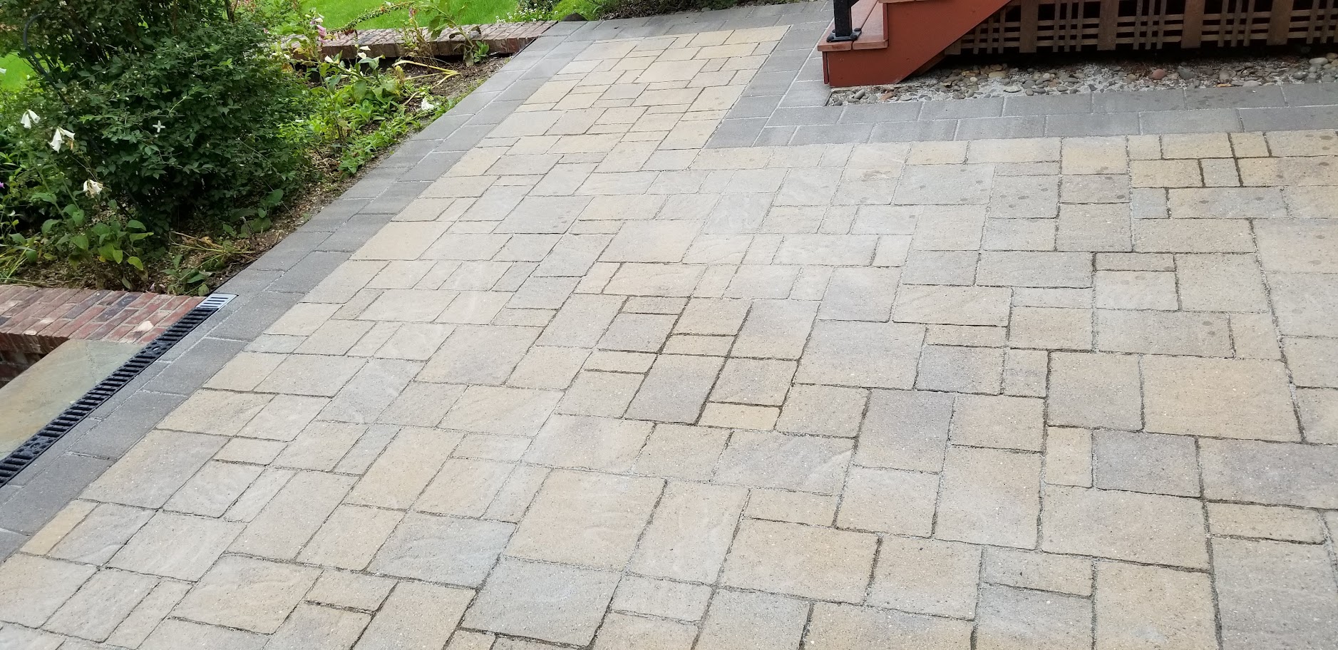 A restored paver patio with clean, re-sanded joints and a contrasting charcoal border course, showing the result of restoration rather than pressure washing alone