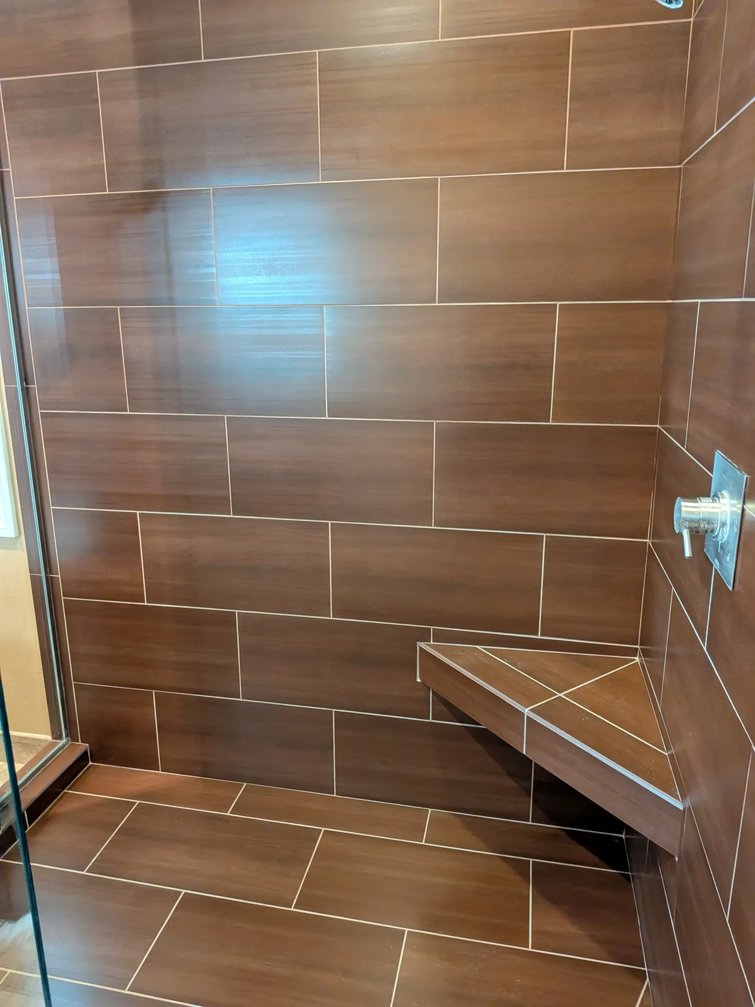 The same brown tiled shower after restoration, the hard water film removed and the tile back to an even deep brown with clean grout lines