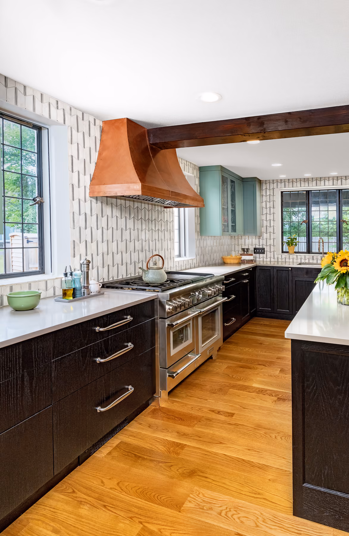 Kitchen with dark cabinetry, a copper range hood, an exposed wood beam, and mint-green upper cabinets in a historic home renovation