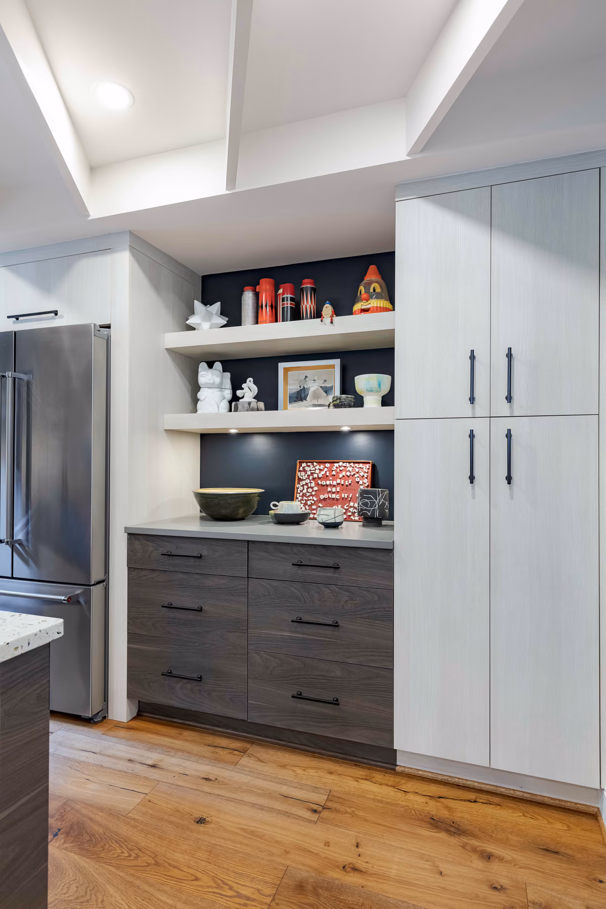 Kitchen nook with floating shelves displaying a curated ceramics collection against a navy accent wall
