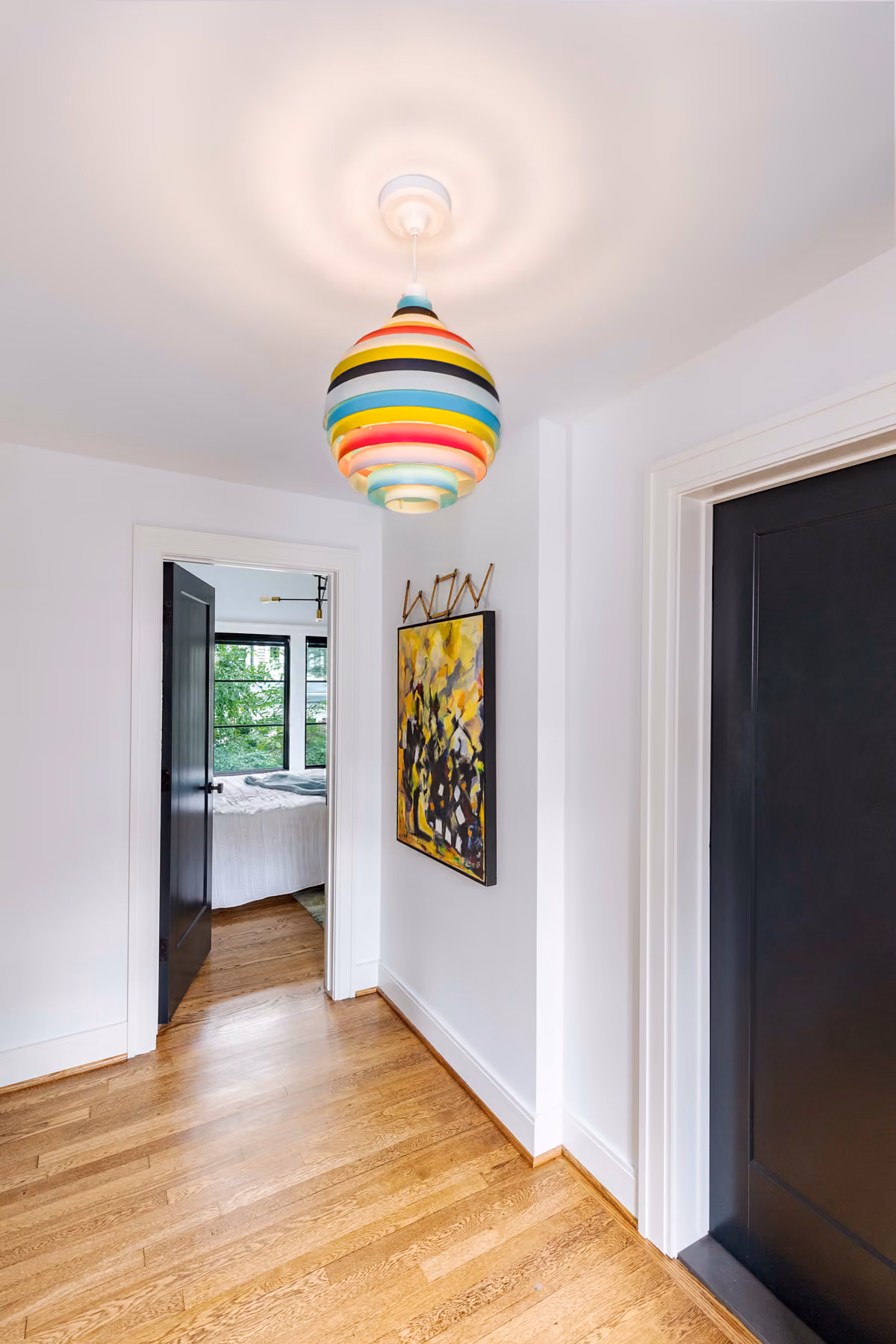 Hallway with a colorful striped globe pendant light and original abstract art
