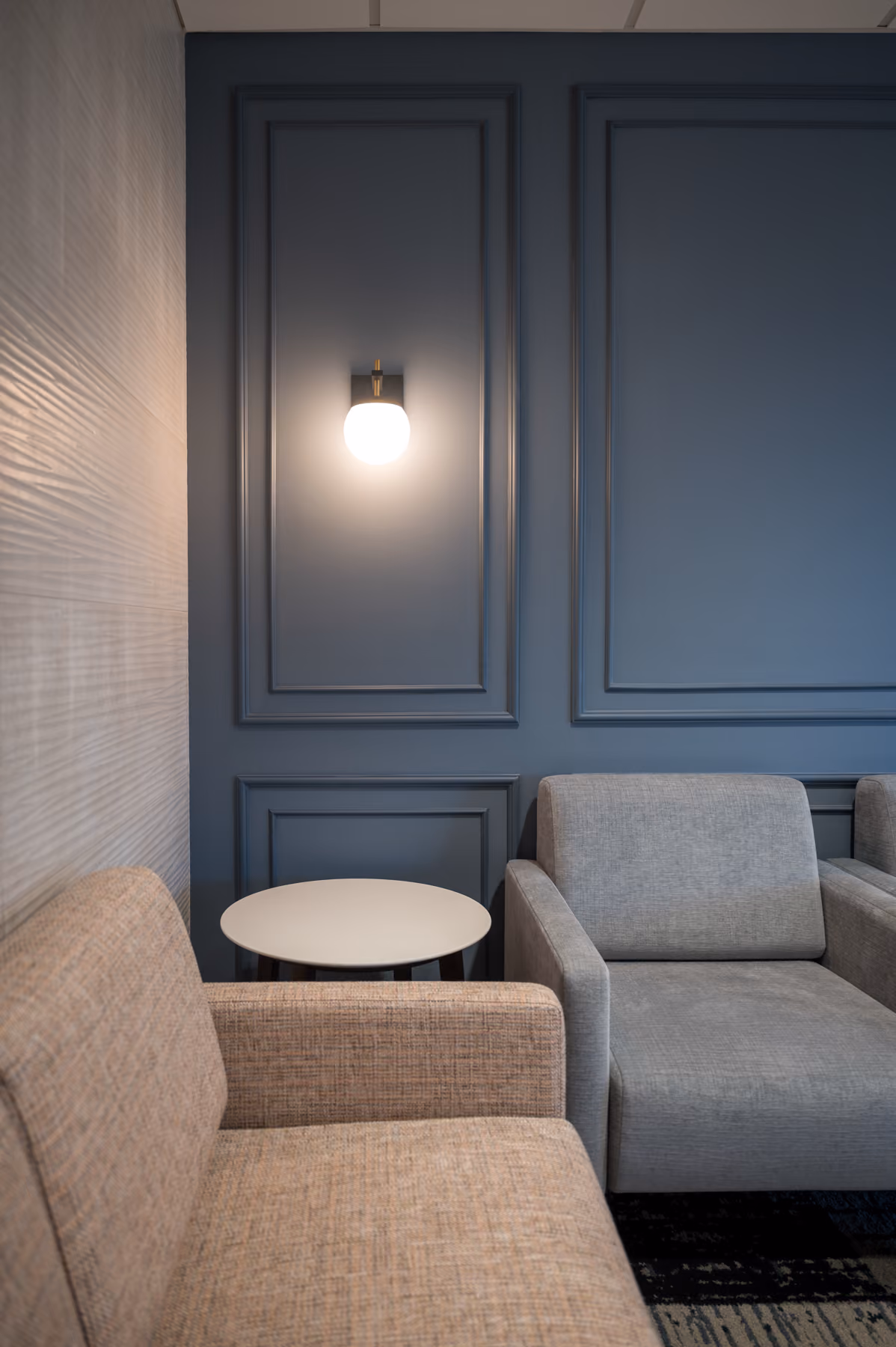Waiting room seating nook with navy paneled walls and a wall sconce