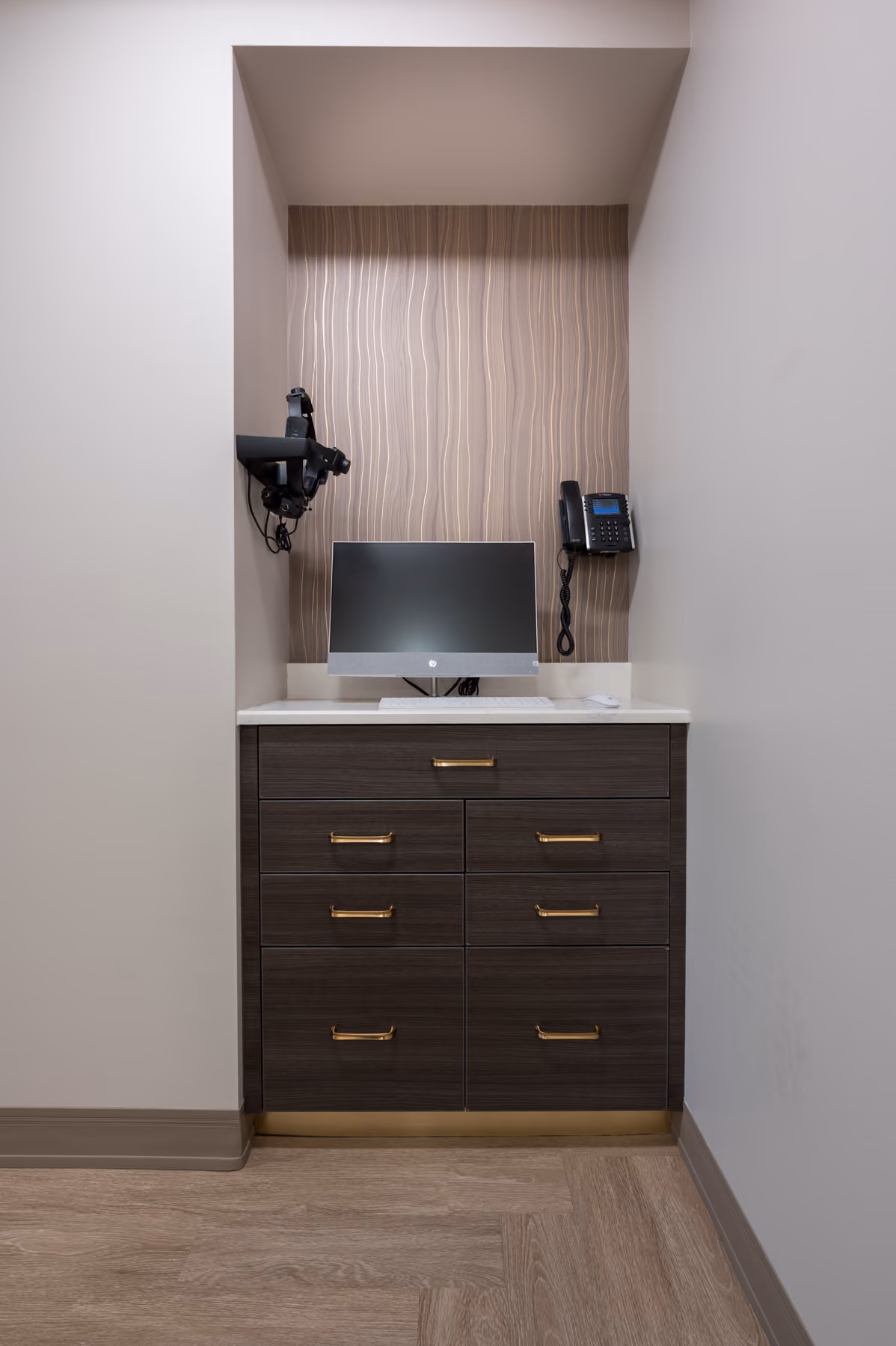 Exam room workstation with dark wood cabinetry, brass hardware, and a built-in computer nook