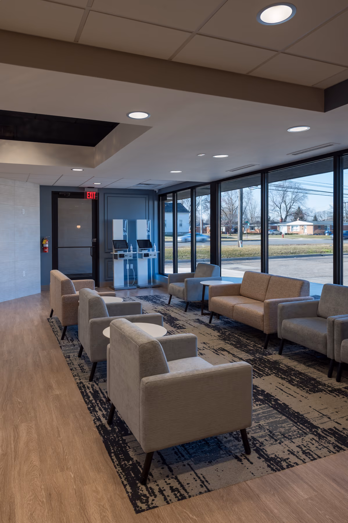 Wide view of the waiting room with floor-to-ceiling windows, a patterned area rug, and upholstered seating groups