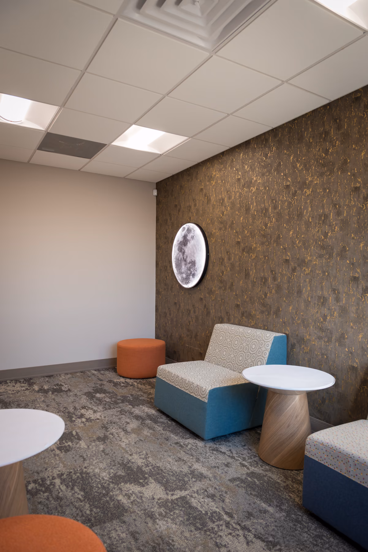 Lounge seating area with moon wall art and modular chairs around round side tables