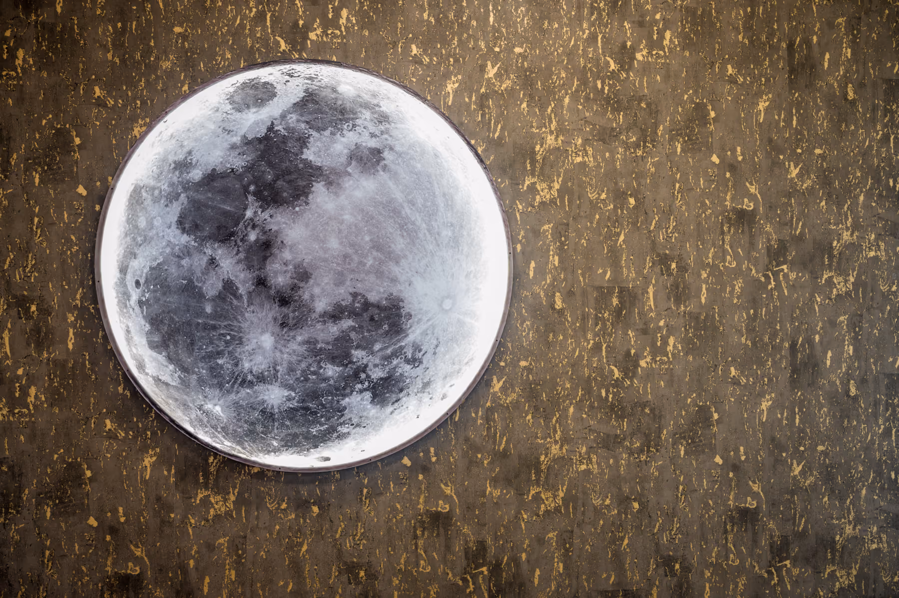 Circular full-moon wall art mounted on a textured bronze wallcovering