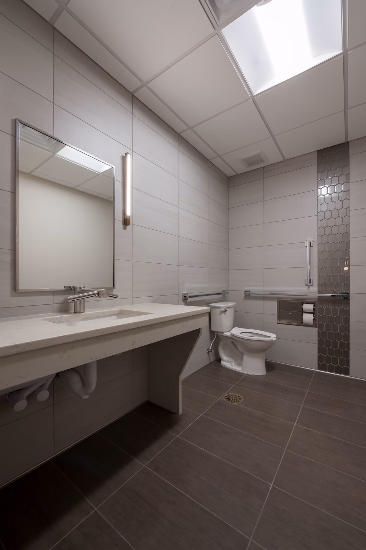 ADA-accessible restroom with a floating vanity, grab bars, and a mosaic tile accent wall