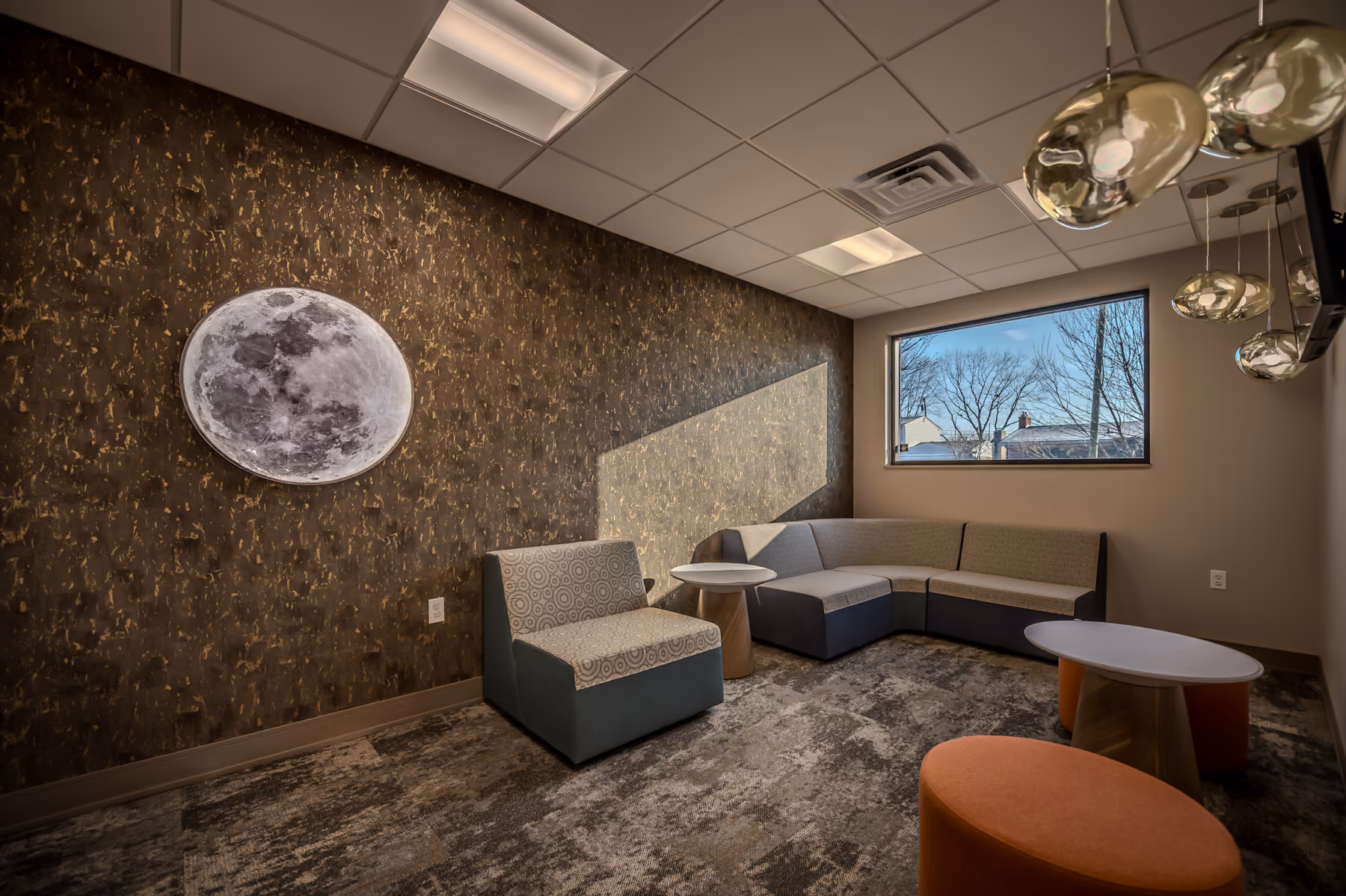 Lounge with moon wall art, a cluster of gold globe pendant lights, and sectional seating