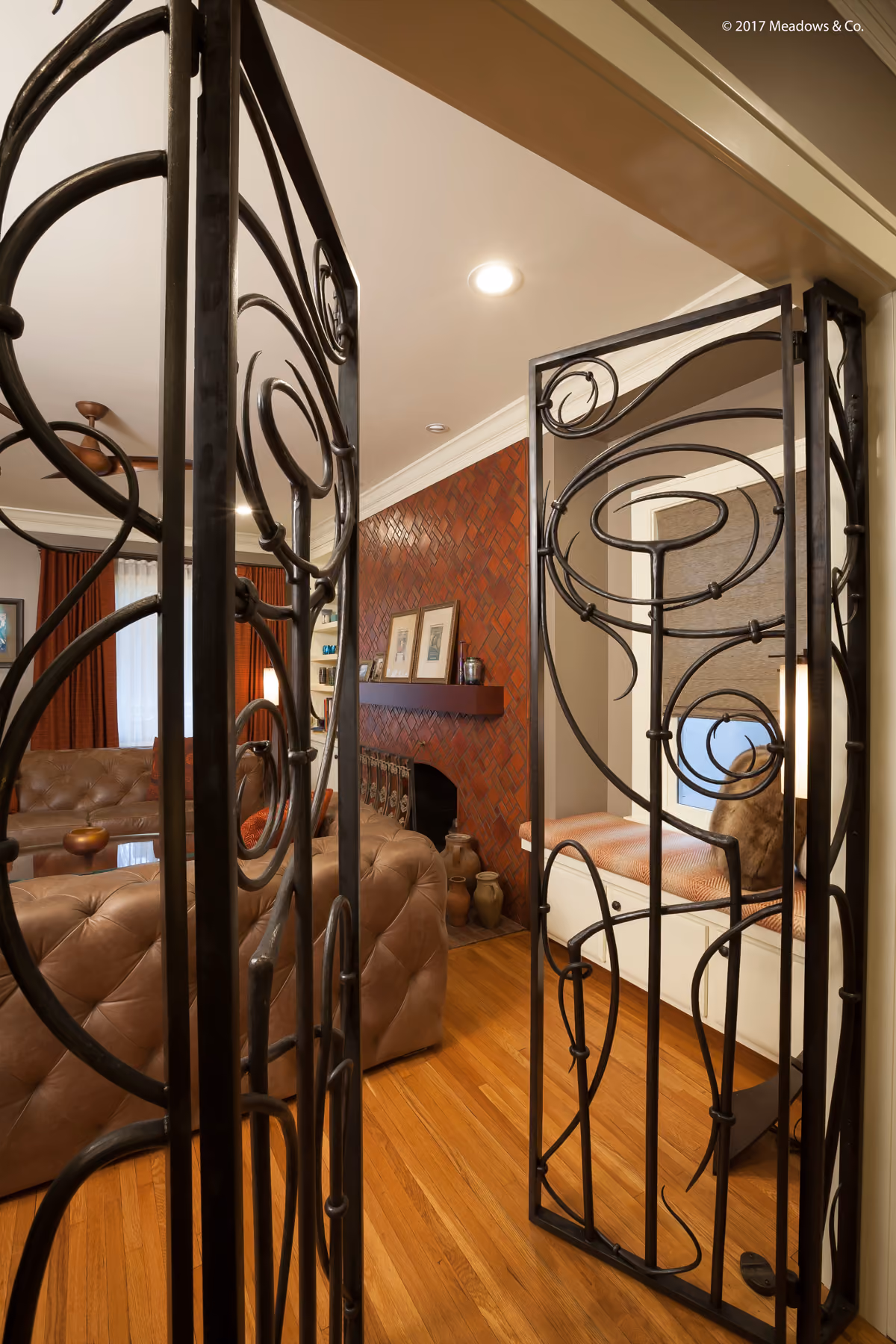 Close view of a custom scrollwork wrought-iron gate dividing the living room from the home office