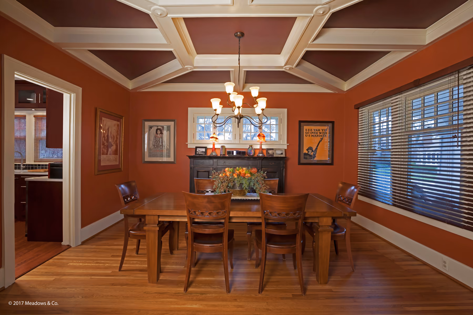 Dining room with terracotta walls, a coffered wood-beam ceiling, and a wood table with leather chairs